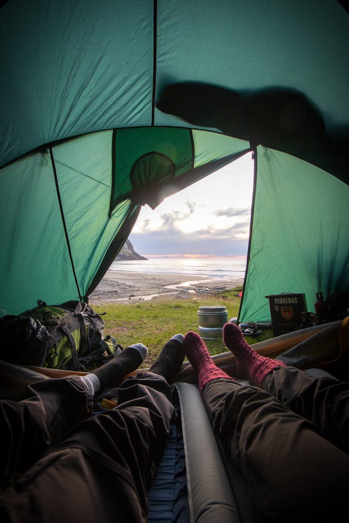 projects-header View from inside a tent overlooking a coastal sunset, capturing a relaxing camping experience.