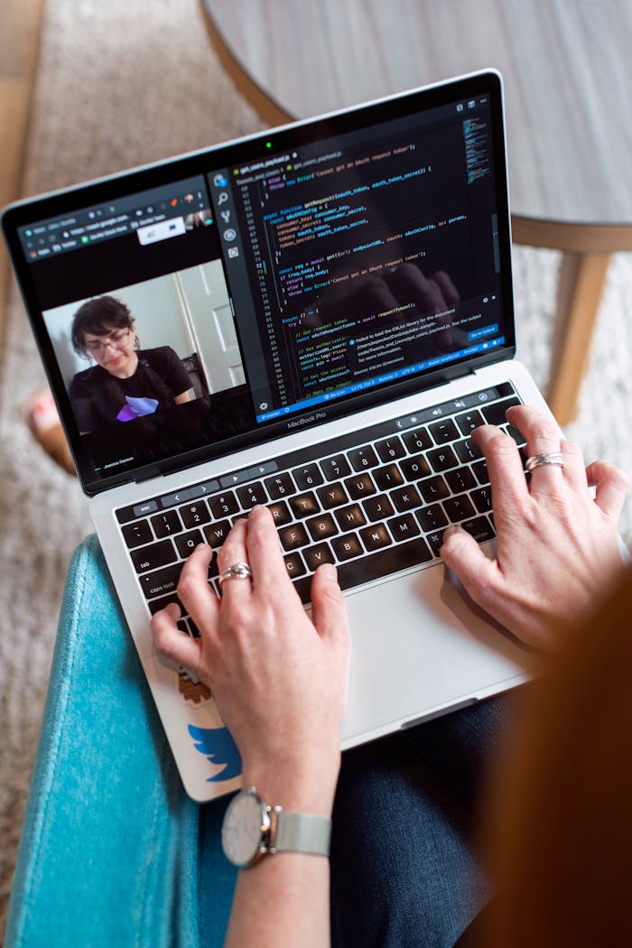 project-02-a Person coding on a laptop during a video conference, showcasing remote work.