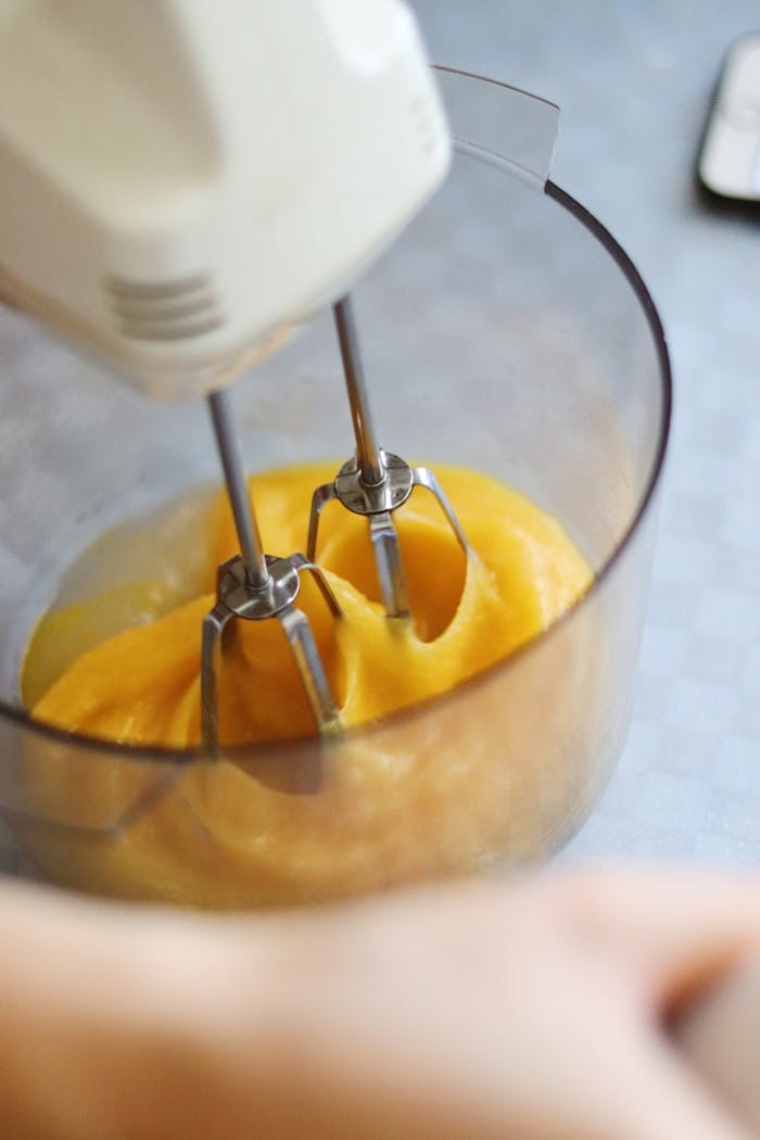 services-header From above of crop anonymous baker using electric mixer while mixing eggs in plastic bowl