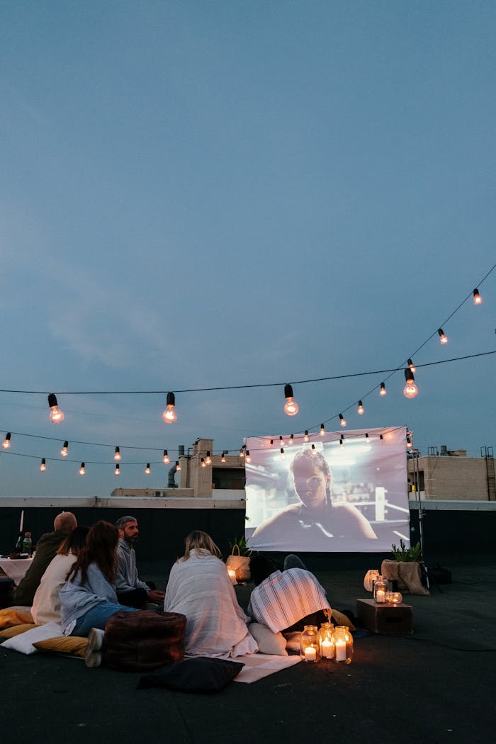 about-03 Group of friends enjoying a cozy rooftop movie night with string lights.